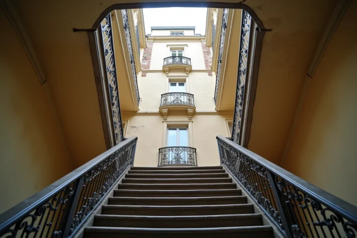 Vue en contre-plongée d'une cage d'escalier haussmannienne illustrant la propagation du bruit entre les étages